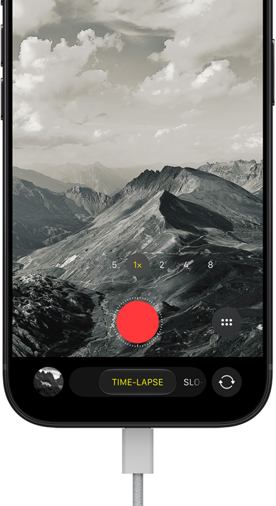 iPhone 18 Pro, front exterior, displaying a mountainous landscape, with the camera mode overlay in Time-Lapse mode, with charging cable attached to charging port